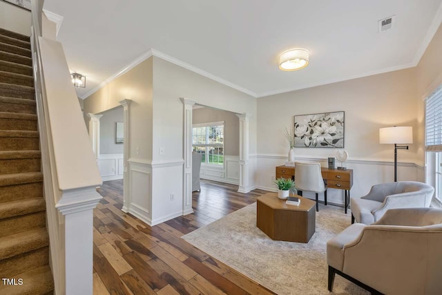 living room featuring dark hardwood / wood-style floors, decorative columns, and crown molding