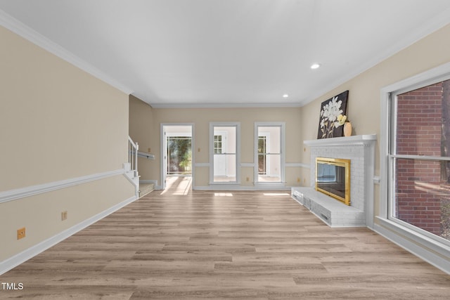 unfurnished living room with a brick fireplace, ornamental molding, and light hardwood / wood-style floors