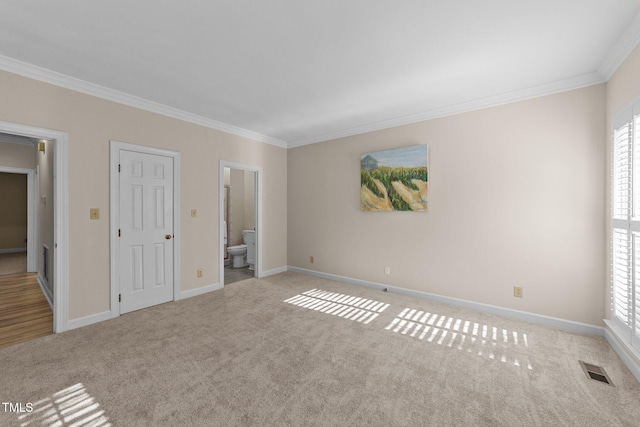 unfurnished bedroom with ornamental molding, light colored carpet, and ensuite bath