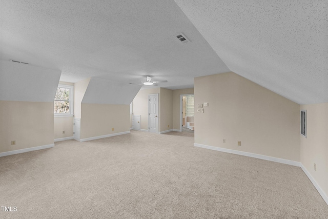 bonus room with a textured ceiling, light colored carpet, and vaulted ceiling