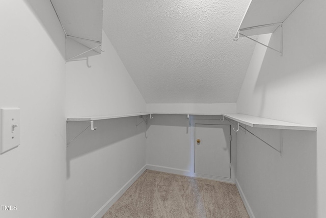 walk in closet featuring lofted ceiling and light carpet