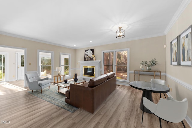 living room featuring a notable chandelier, light wood-type flooring, and ornamental molding