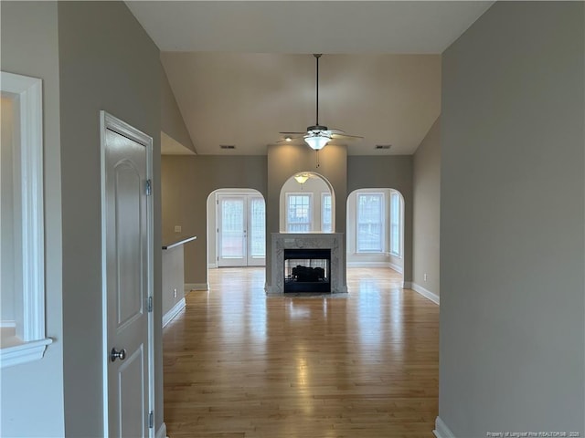 unfurnished living room featuring lofted ceiling, a fireplace, ceiling fan, and light wood-type flooring