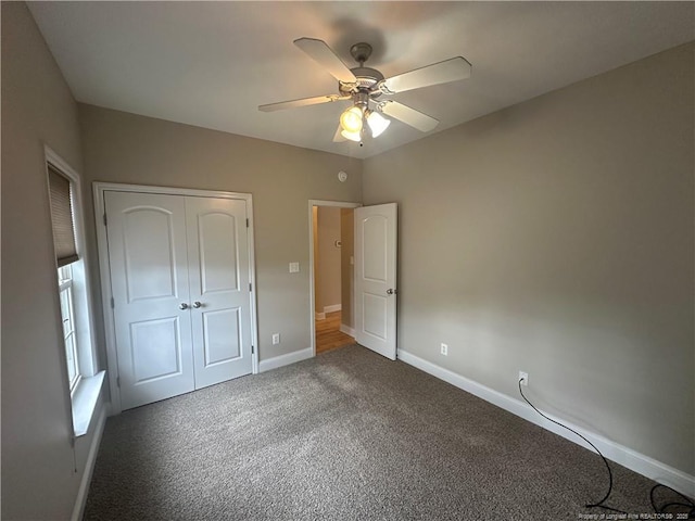 unfurnished bedroom with ceiling fan, a closet, and dark colored carpet