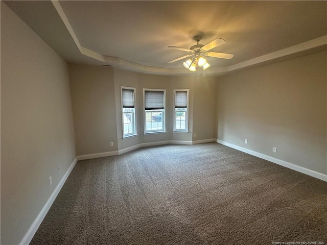 carpeted empty room featuring a raised ceiling and ceiling fan