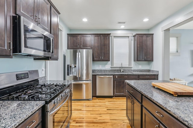 kitchen featuring sink, dark brown cabinetry, appliances with stainless steel finishes, and dark stone countertops