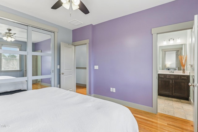 bedroom featuring ceiling fan, light wood-type flooring, and ensuite bathroom