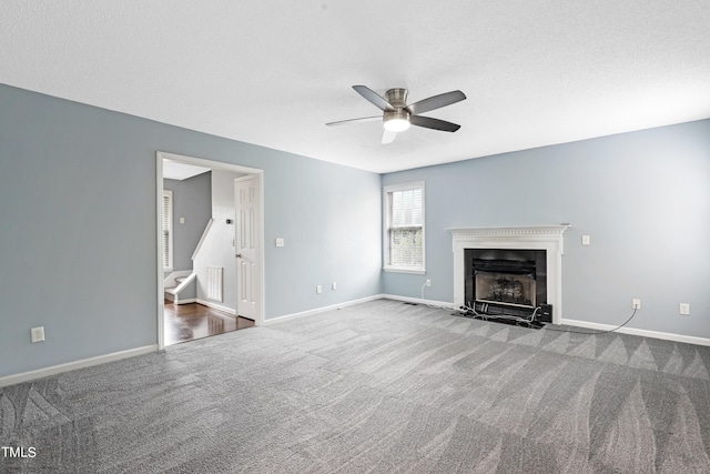 unfurnished living room with ceiling fan, carpet floors, and a textured ceiling