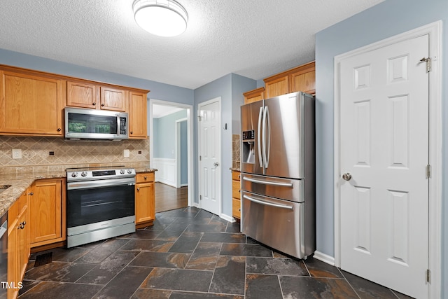 kitchen featuring light stone counters, a textured ceiling, appliances with stainless steel finishes, and tasteful backsplash