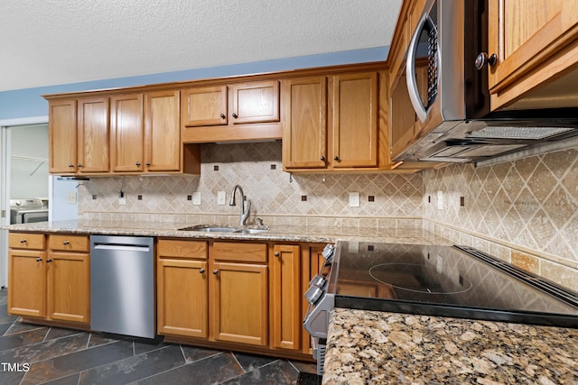 kitchen with sink, light stone countertops, a textured ceiling, stainless steel appliances, and washing machine and clothes dryer