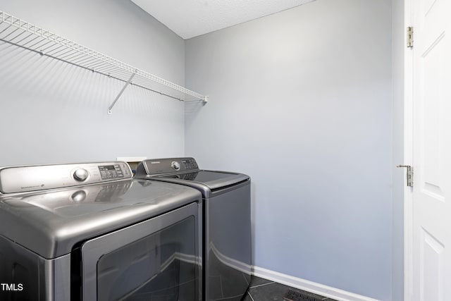 washroom with washer and clothes dryer, dark tile patterned floors, and a textured ceiling