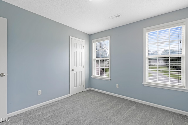 carpeted empty room featuring a textured ceiling