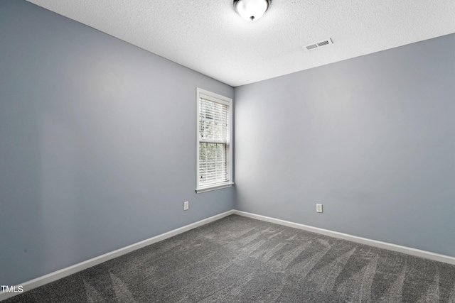 spare room with dark colored carpet and a textured ceiling