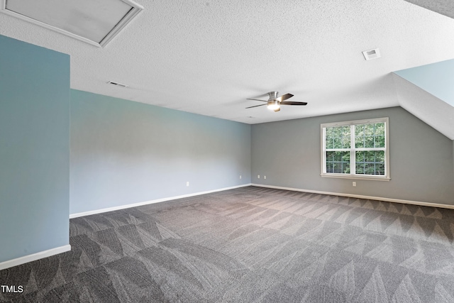 unfurnished room with vaulted ceiling, ceiling fan, a textured ceiling, and dark colored carpet