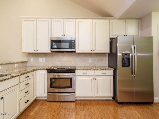 kitchen with light stone countertops, stainless steel appliances, tasteful backsplash, light hardwood / wood-style floors, and vaulted ceiling