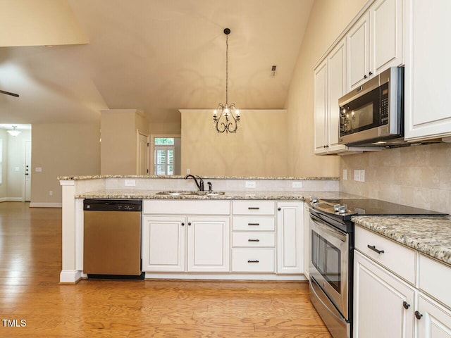 kitchen featuring kitchen peninsula, light wood-type flooring, stainless steel appliances, sink, and hanging light fixtures