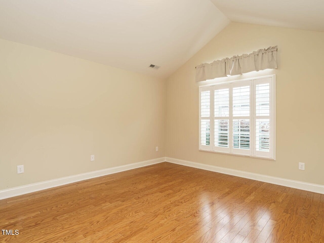 unfurnished room with hardwood / wood-style floors and lofted ceiling