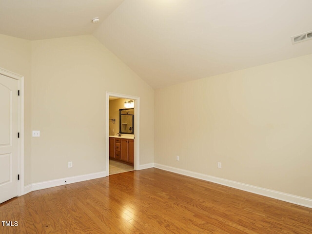 unfurnished room with light wood-type flooring and lofted ceiling