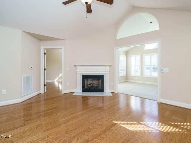 unfurnished living room featuring hardwood / wood-style floors, ceiling fan, a premium fireplace, and vaulted ceiling