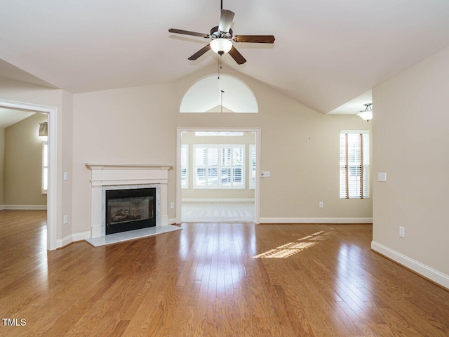 unfurnished living room with ceiling fan, light hardwood / wood-style floors, a premium fireplace, and lofted ceiling