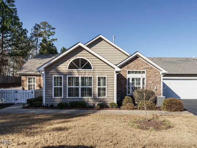 view of front facade with a garage, central air condition unit, and a front lawn