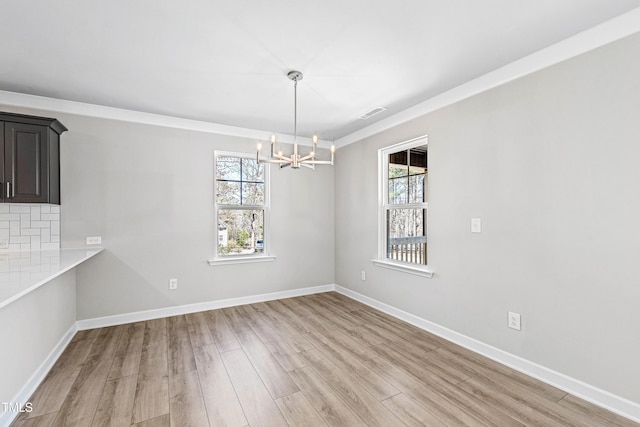 unfurnished dining area with light wood finished floors, plenty of natural light, and baseboards