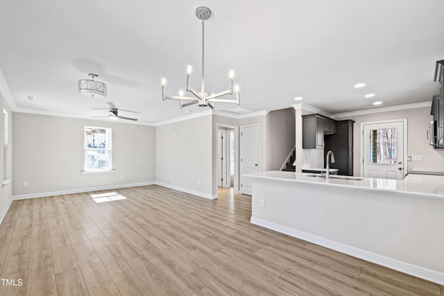 kitchen with ceiling fan, a sink, baseboards, light wood-style floors, and crown molding