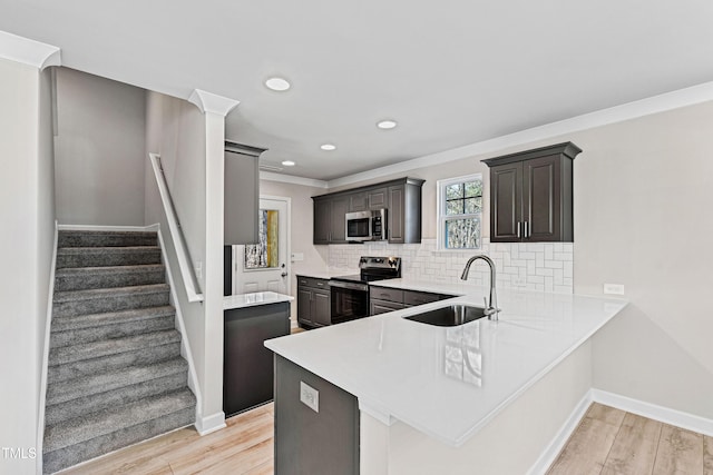 kitchen with stainless steel appliances, a sink, light countertops, light wood-type flooring, and decorative backsplash