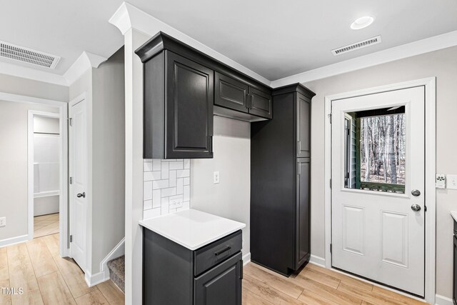 kitchen featuring light countertops, backsplash, visible vents, and light wood-style floors