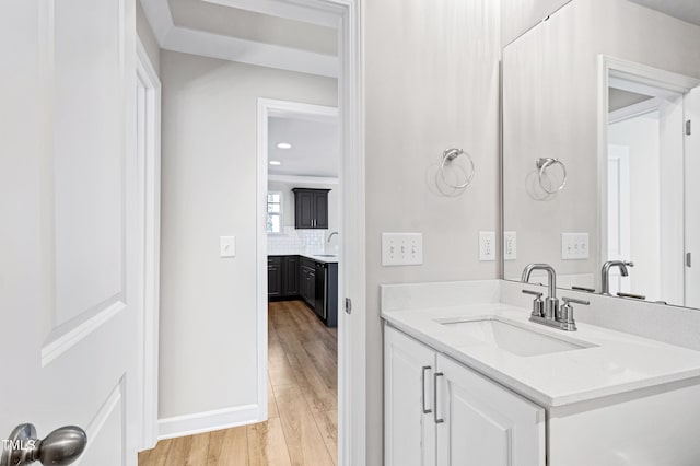 bathroom featuring tasteful backsplash, vanity, baseboards, and wood finished floors