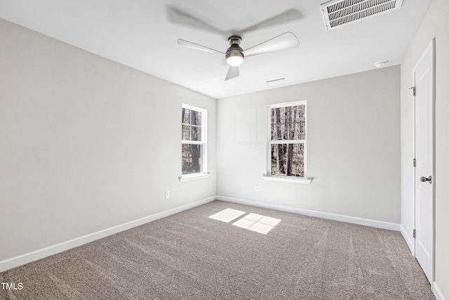 spare room with carpet floors, visible vents, and baseboards