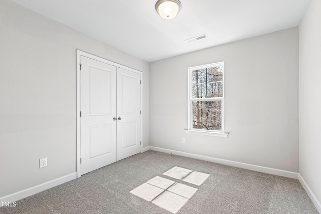 unfurnished bedroom featuring carpet floors, a closet, visible vents, and baseboards