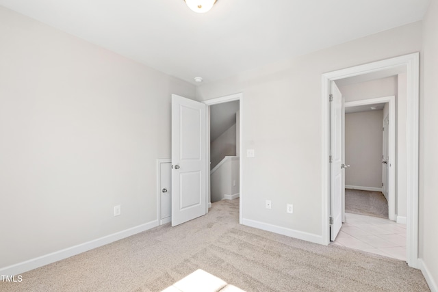 unfurnished bedroom featuring carpet floors, baseboards, and tile patterned floors