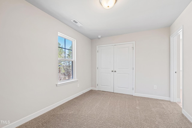 unfurnished bedroom with carpet, a closet, visible vents, and baseboards