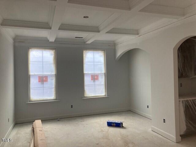 unfurnished room featuring beam ceiling, a healthy amount of sunlight, and coffered ceiling