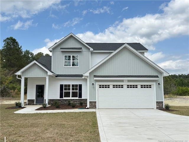 view of front of home with stone siding, driveway, a front lawn, and an attached garage