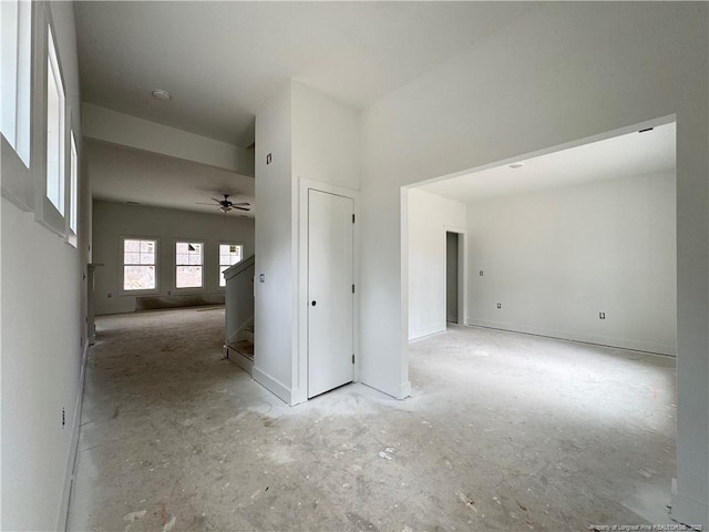 spare room featuring a ceiling fan, baseboards, and stairs
