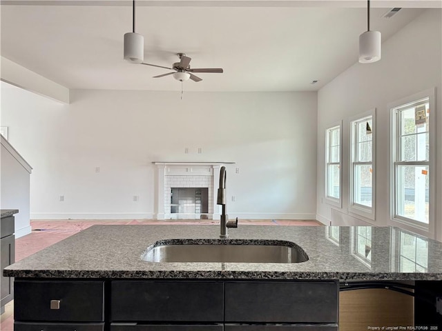 kitchen featuring open floor plan, a sink, stone counters, and ceiling fan