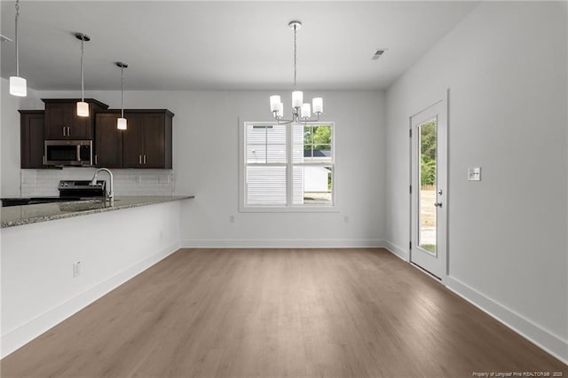 1585 Scull Rd, Raeford, NC 28376 - kitchen featuring appliances with stainless steel finishes, light wood-style flooring, backsplash, light stone countertops, and a chandelier