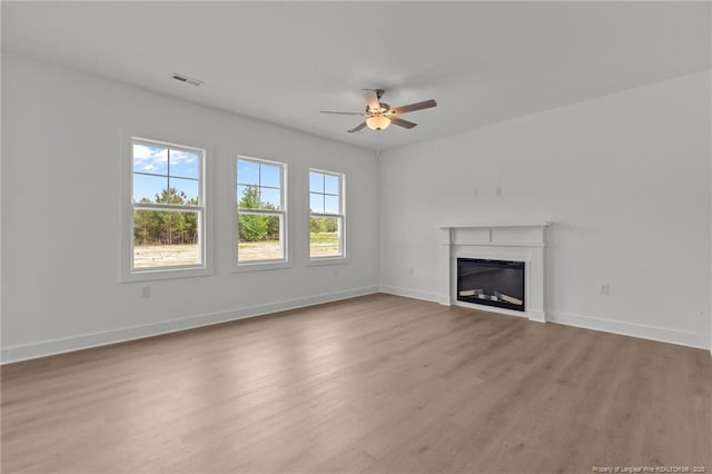 1585 Scull Rd, Raeford, NC 28376 - unfurnished living room with a ceiling fan, wood finished floors, a glass covered fireplace, and baseboards
