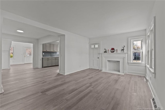 unfurnished living room featuring light hardwood / wood-style floors and a brick fireplace