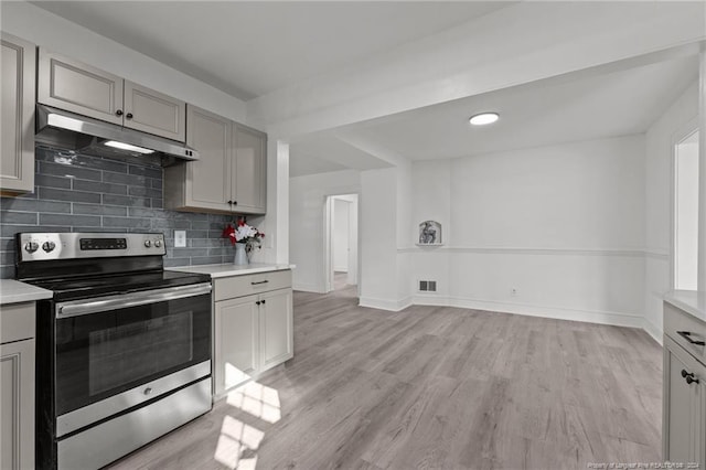 kitchen with gray cabinetry, light wood-type flooring, electric stove, and backsplash