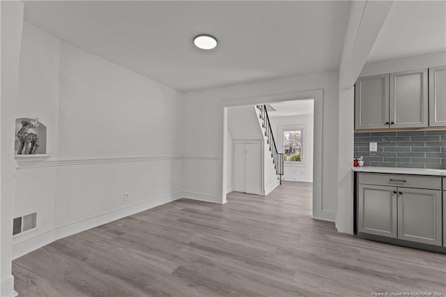 kitchen with light wood-type flooring, gray cabinets, and tasteful backsplash