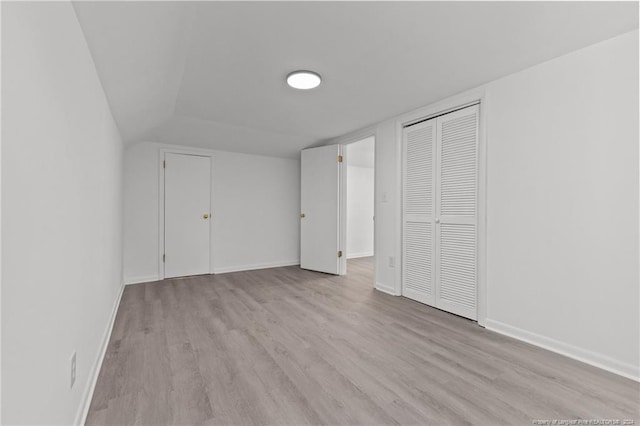 unfurnished bedroom with lofted ceiling and light wood-type flooring