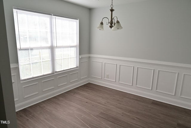 unfurnished room featuring a wealth of natural light, dark hardwood / wood-style floors, and an inviting chandelier