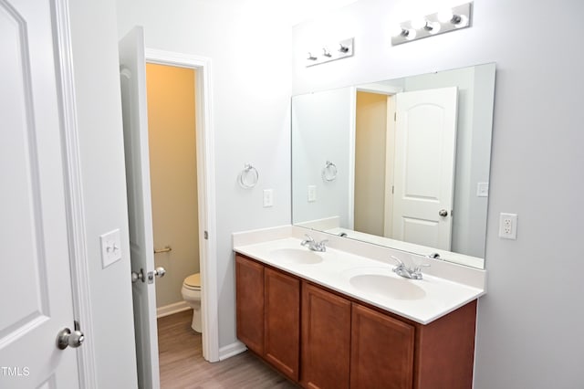 bathroom with vanity, toilet, and wood-type flooring