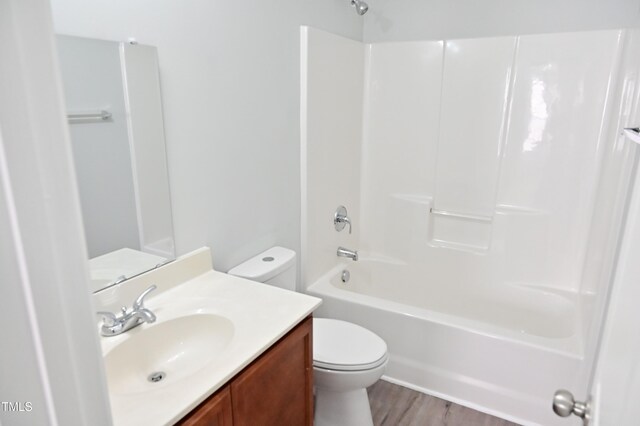 full bathroom with hardwood / wood-style floors, vanity,  shower combination, and toilet