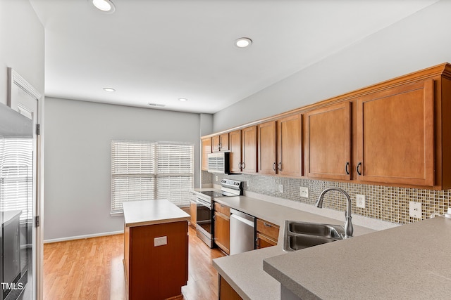 kitchen featuring sink, backsplash, light hardwood / wood-style floors, a kitchen island, and appliances with stainless steel finishes