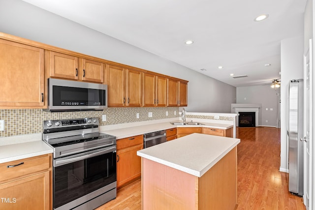 kitchen featuring light wood-type flooring, appliances with stainless steel finishes, a center island, and sink