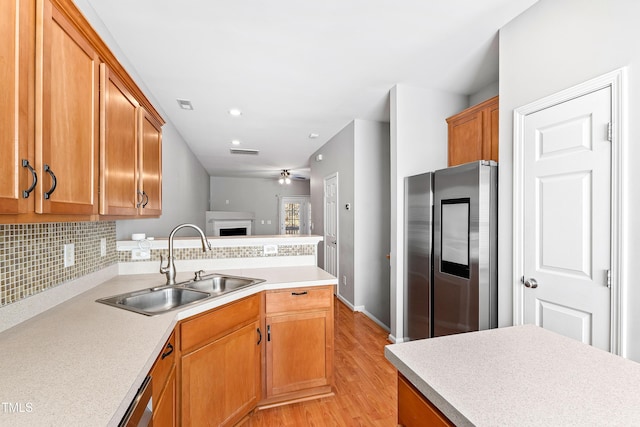 kitchen with tasteful backsplash, ceiling fan, sink, light hardwood / wood-style flooring, and stainless steel fridge with ice dispenser